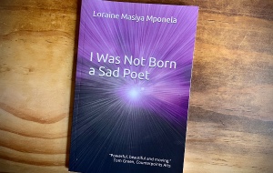 A purple book on a desk called I Was Not Born a Sad Poet by Loraine Masiya Mponela