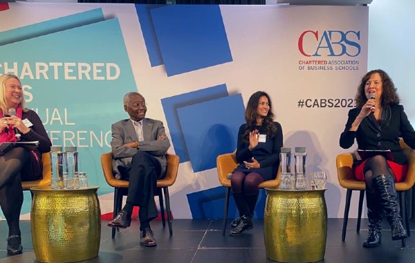 4 people seated on stage at a conference