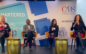 4 people seated on stage at a conference