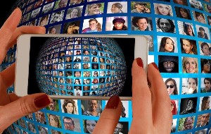 A phone photographing a spherical image of people on screens