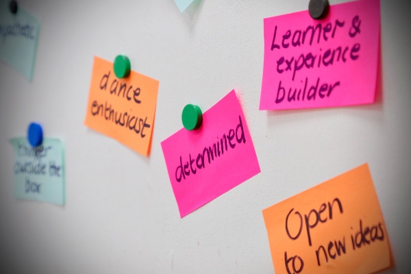 A whiteboard with colours sticky fixers on which people have written their characteristics